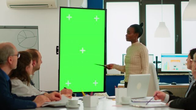 Greenscreen, analytics and businesswoman using a pointer beside a vertical chroma key display during team presentation, for data discussion, project strategy, custom graphics and office communication.