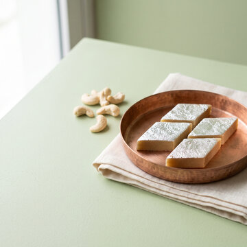 Kaju katli cashew sweets on a copper plate with copy space