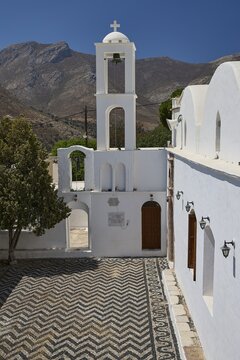 Taxiarchis, Church of the Archangel, bell tower rises above white buildings and mosaic floor with mountain backdrop, Megalo Chorio, Zero Waste Island, Tilos, Dodecanese, Greek Islands, Greece