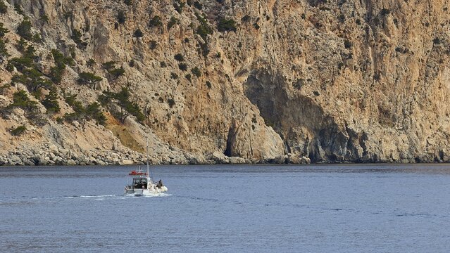A boat sails along a steep rocky coast in the distance, boat tour Saria, Saria Island, Karpathos, Dodecanese, Greek Islands, Greece