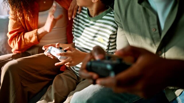 Closeup hands gaming controllers. African american family playing console home.