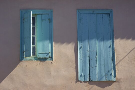 Two old wooden windows on a pastel wall, one opened, in minimalist style, Navarino Bay, Pylos, Peloponnese, Greece