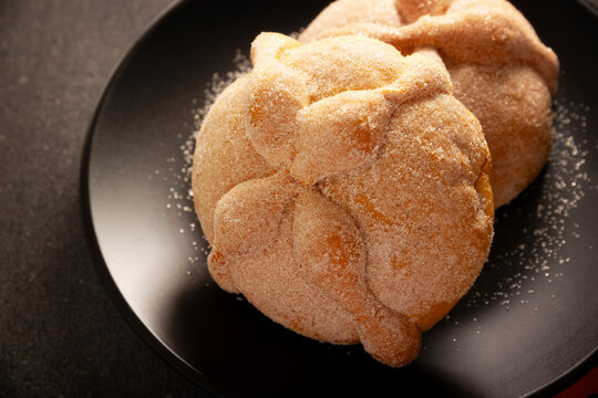 Mexican Pan de Muerto sweet breads on a matte black plate for Day of the Dead Ofrenda.