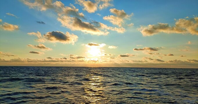 Golden Sunset over Calm Ocean Horizon with Dramatic Clouds