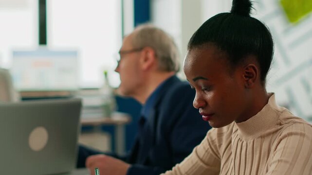 Smiling, businesswoman and portrait focus on a seated professional with direct eye contact while a colleague works behind, suited to confidence, teamwork, communication and workplace culture.
