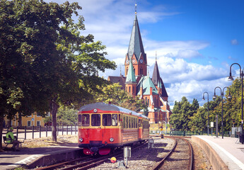 Historic Red Railbus at Västervik Railway Station with St Gertrude Church in Sweden © mojolo
