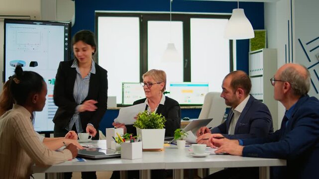 Paperwork, analysis and teamwork with business professionals reviewing documents around a conference table in a modern office for planning, discussion, project coordination and decision making.