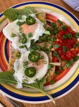 Plate of breakfast food with toast and poached eggs and various fresh vegetables
