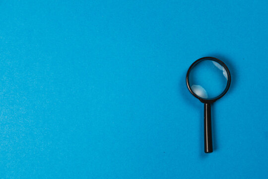 Magnifying glass placed on blue background showing focus on details