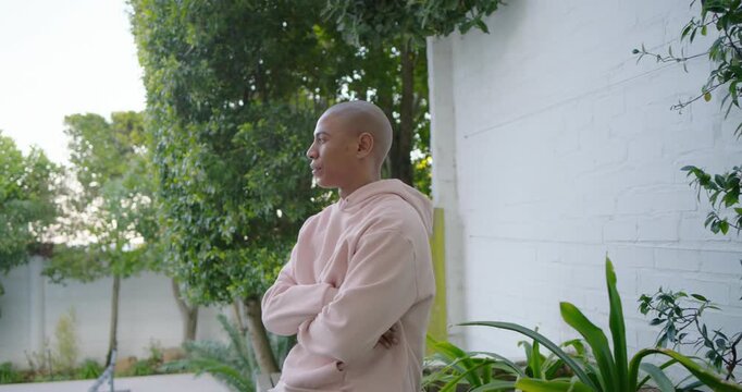 African American man leaning on wall in garden gazing shifting toward camera engaging, copy space