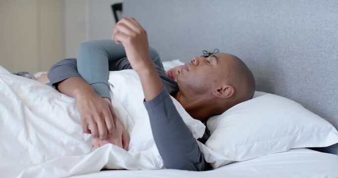 African American men spooning in bed, front man moving rear holding adjusting grip seeking comfort