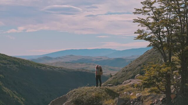 W Trek hiker standing at a viewpoint overlooking the rugged mountain landscape below, Torres del Paine, Patagonia, Chile
