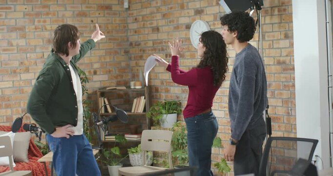 Loft team rehearsing left man pointing, center woman holding script arguing, right man mediating