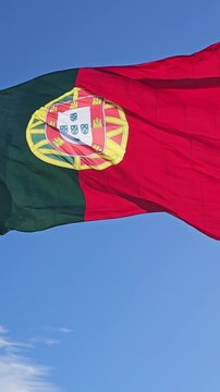 Portugal flag waving and rippling in the wind in clear blue sky close-up vertical video