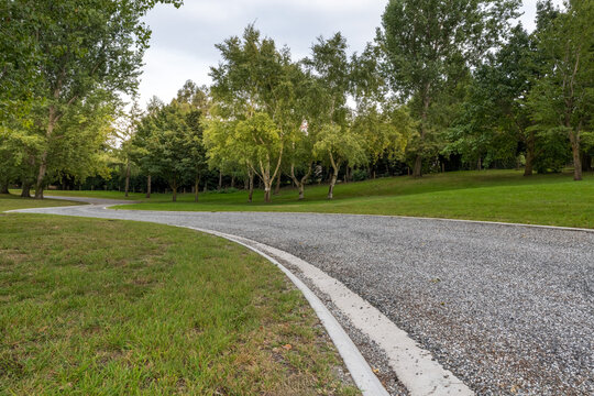 Road background, automotive backplate, curved driveway  in parklike setting featuring mowed lawns and trees