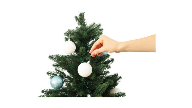 A Close-Up View of a Person Placing a Decorative Ornament onto a Small Green Christmas Tree against a White Background