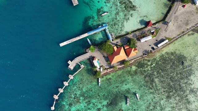 Aerial view of the passenger ferry port with turquoise water, coral reefs, and small boats in Karimunjawa, Central Java, Indonesia.