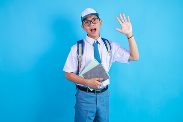 An Asian High School Male Student Waving Raised Hand While Carrying Books © Gatot