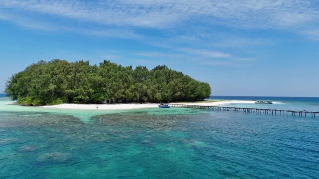 Aerial view of Pulau Cilik, a remote tropical island with a wooden pier and turquoise waters in Karimunjawa, Central Java, Indonesia.