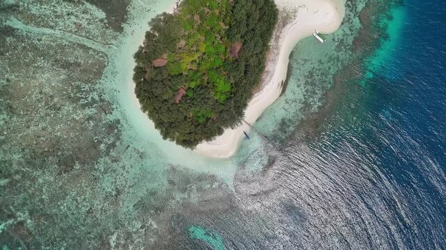 Aerial view of Pulau Cilik island with lush greenery, white sand beach, and turquoise water surrounded by coral reefs in Karimunjawa, Central Java, Indonesia.