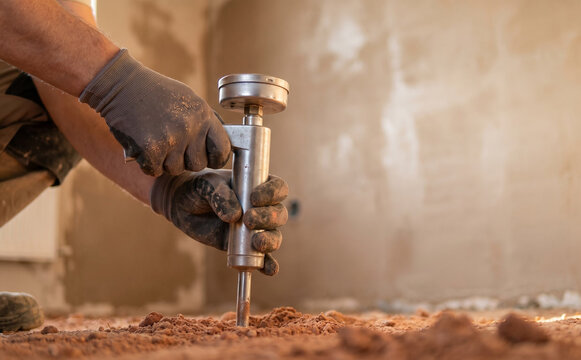 Worker testing soil compaction using dynamic probe penetrometer on construction site