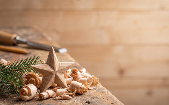Handmade wooden Christmas star with shavings and fir branch on workshop workbench
