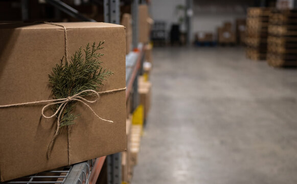 Wrapped cardboard shipping box with pine branch decoration in warehouse fulfillment center for holiday logistics