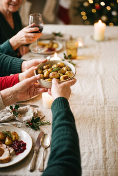 Family dinner sharing a bowl of roasted potatoes during holiday feast celebration