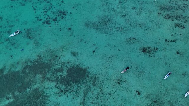 Aerial view of small boats floating in clear turquoise water in Karimunjawa, Central Java, Indonesia.