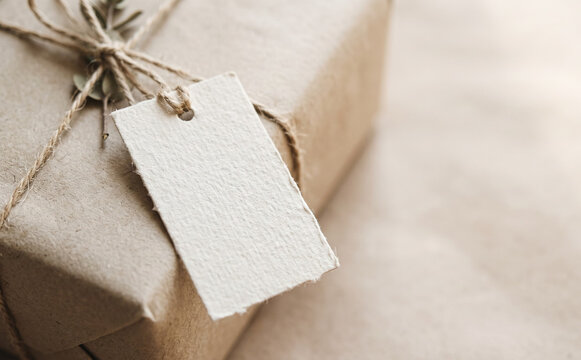 Wrapped gift box with brown paper and a blank paper tag mockup for present concepts and holidays