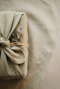 Eco friendly gift wrapping with green fabric, linen cloth, and dry eucalyptus branch for sustainable packaging