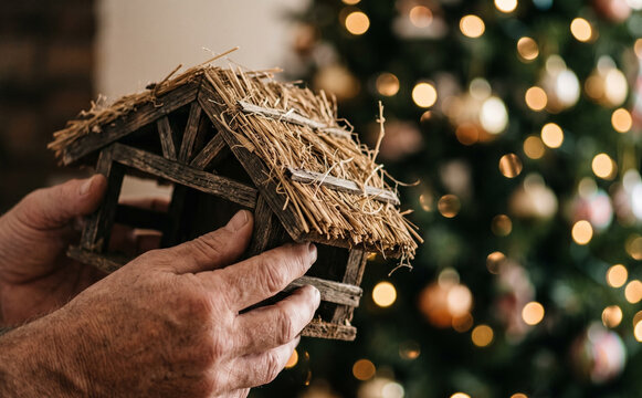 Man holding a miniature wooden manger with straw representing Christmas nativity scene and holidays