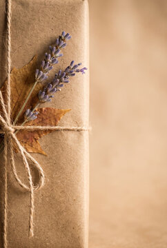 Rustic gift box wrapped in brown paper decorated with lavender flowers and dry autumn leaf