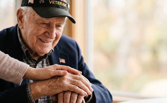 Elderly veteran smiling while receiving compassionate support and care from a caregiver