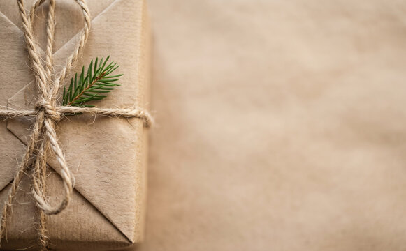 Rustic brown craft paper gift box wrapped with twine string and a pine branch for holidays