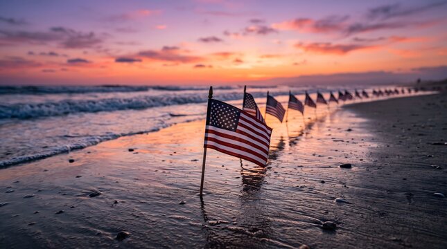 A row of american flags planted in the wet sand of a beach at sunset, with a beautiful colorful sky and ocean waves in the background