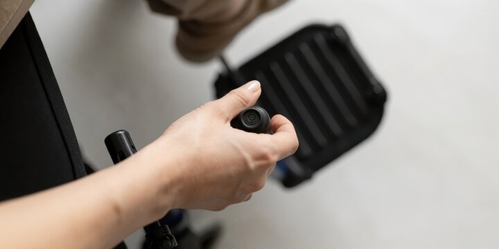 Disabled woman operating electric wheelchair using joystick control device indoors close up