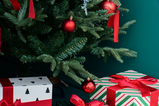 Red Christmas Ornaments Hang Above Gifts Beneath the Tree