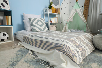Childhood development and home interior design, cozy bedroom for kids with teepee tent and floor bed in a modern nursery room for play and sleep © Pixel-Shot