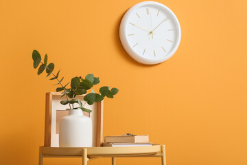 Time management and productivity concept, modern interior decor with wall clock and eucalyptus plant on table against orange background © Pixel-Shot