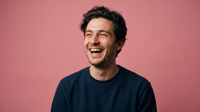 Young man laughing happily with big smile portrait pink background