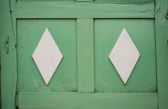 Detalle de puerta de madera verde con rombos blancos, patr&oacute;n geom&eacute;trico de fachada colonial