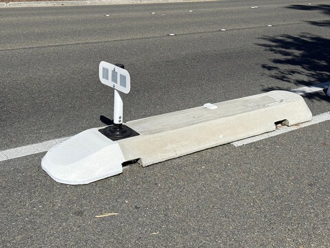 Concrete lane divider with reflective bollard on asphalt road