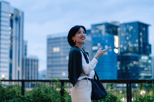 Business asian woman relax using smartphone social network communication metropolis city building background