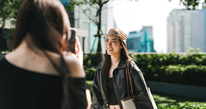 Happy two young asian woman gen z sisters using smartphone taking photo sibling share travel moment on social media engagement