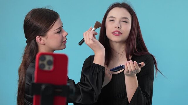 Two Young Women Recording Makeup Tutorial Video on Smartphone in Studio