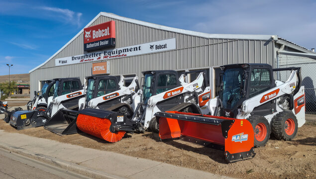 DRUMHELLER, CANADA - 03 OCTOBER 2026: Bobcat skid steer loaders lineup with attachments at Drumheller Equipment dealership in Alberta Canada