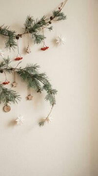 Rustic christmas garland made of evergreen twigs and dried fruit hanging on white wall with copy space