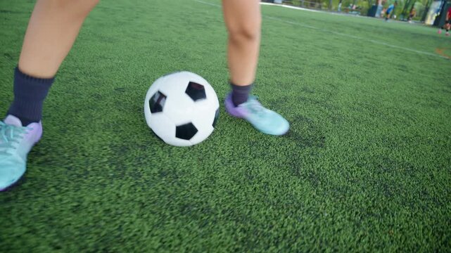 Close-up of a boy kicking a soccer ball on a green turf field, with sharp detail and frozen motion, representing youth sports, training, fitness and a healthy active lifestyle.