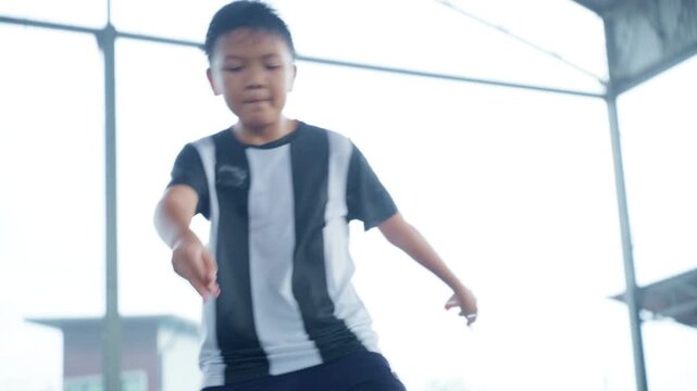 Close-up of a boy kicking a soccer ball on a green turf field, with sharp detail and frozen motion, representing youth sports, training, fitness and a healthy active lifestyle.